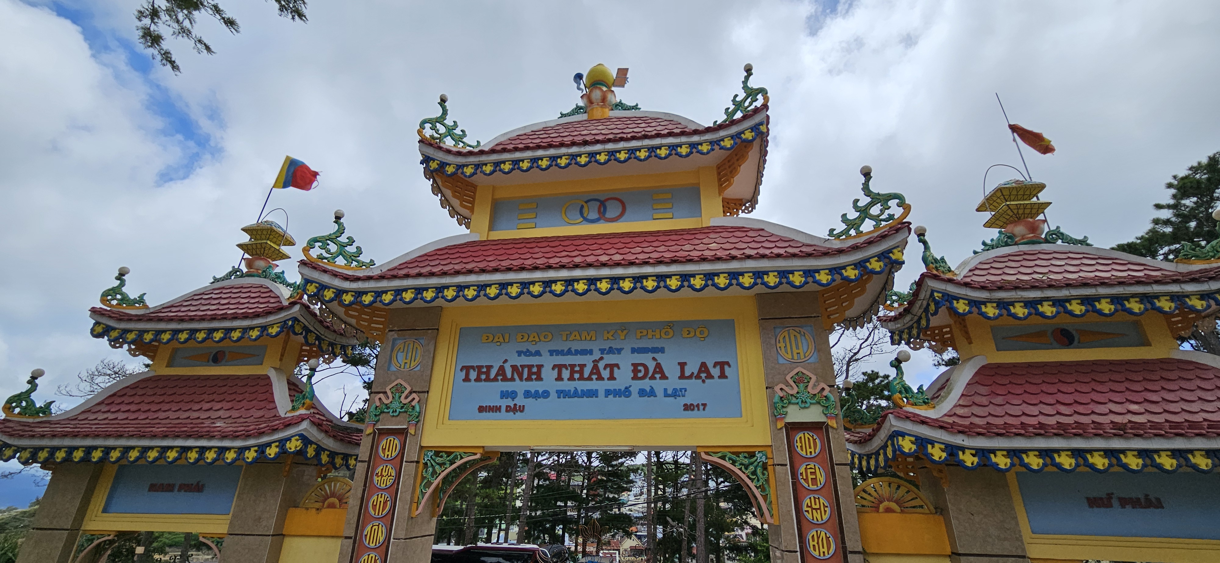 Colorful entrance gate of a temple complex in Da Lat, Vietnam, featuring traditional Asian architectural elements and inscriptions.