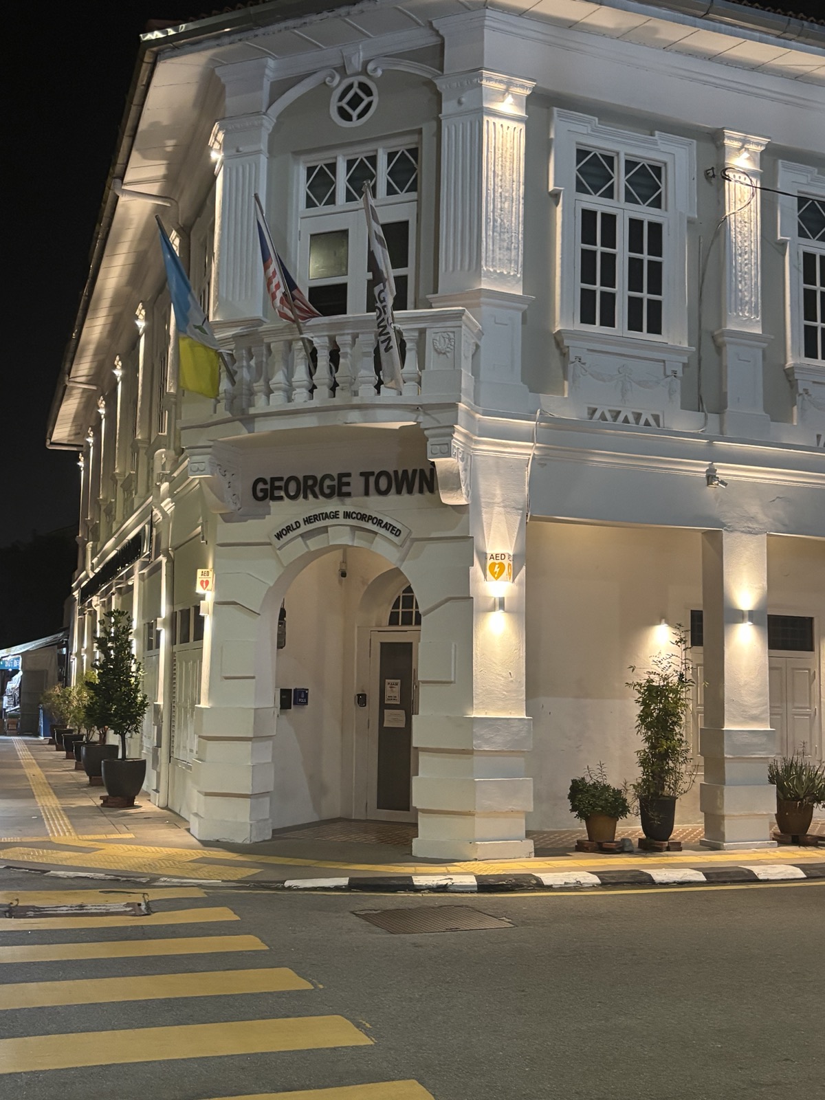 Illuminated colonial-style building at night with the sign 'GEORGE TOWN' and flags on display.